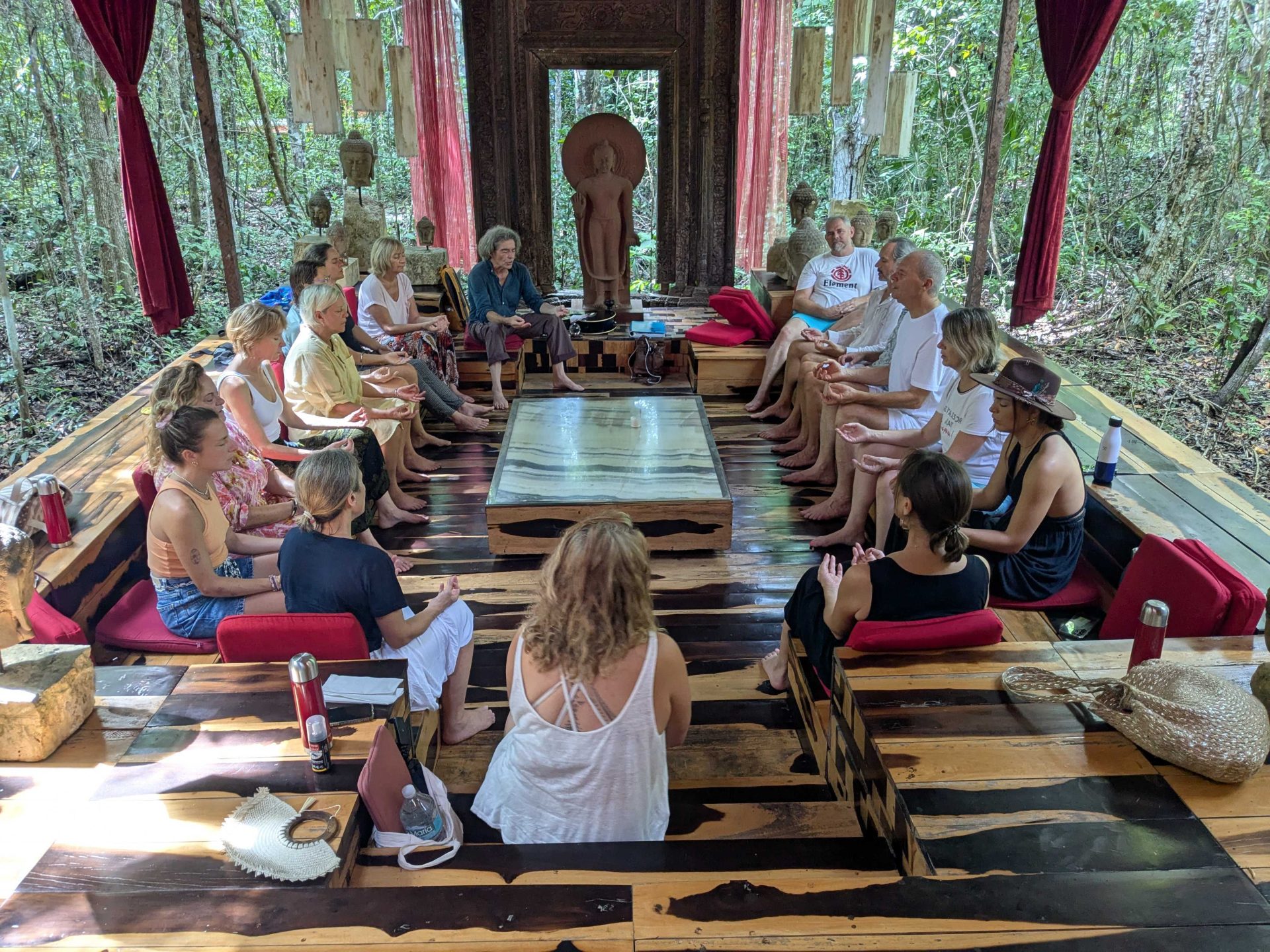 Groupe méditant dans un pavillon en forêt.